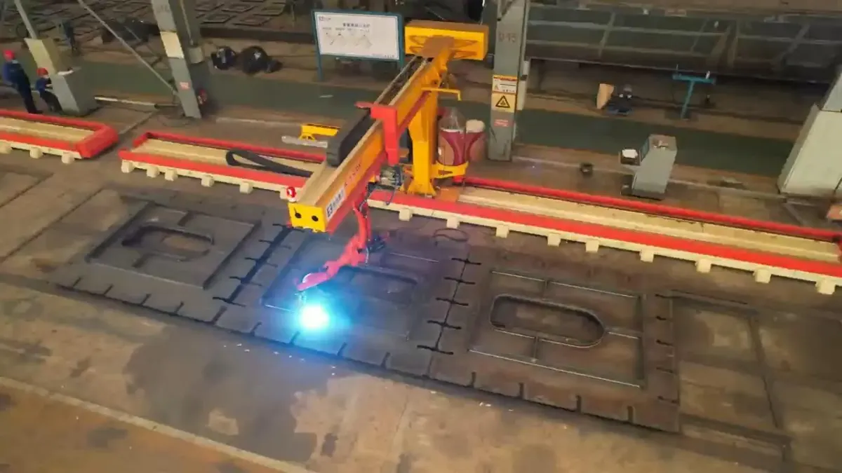 Cantilever welding station above a steel plate panel, with the welding arc visible.