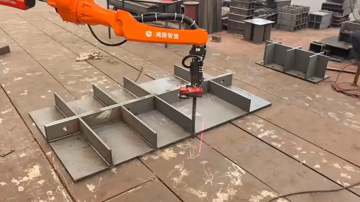 Orange robot arm above a grid of steel diaphragm plates on the shop floor.