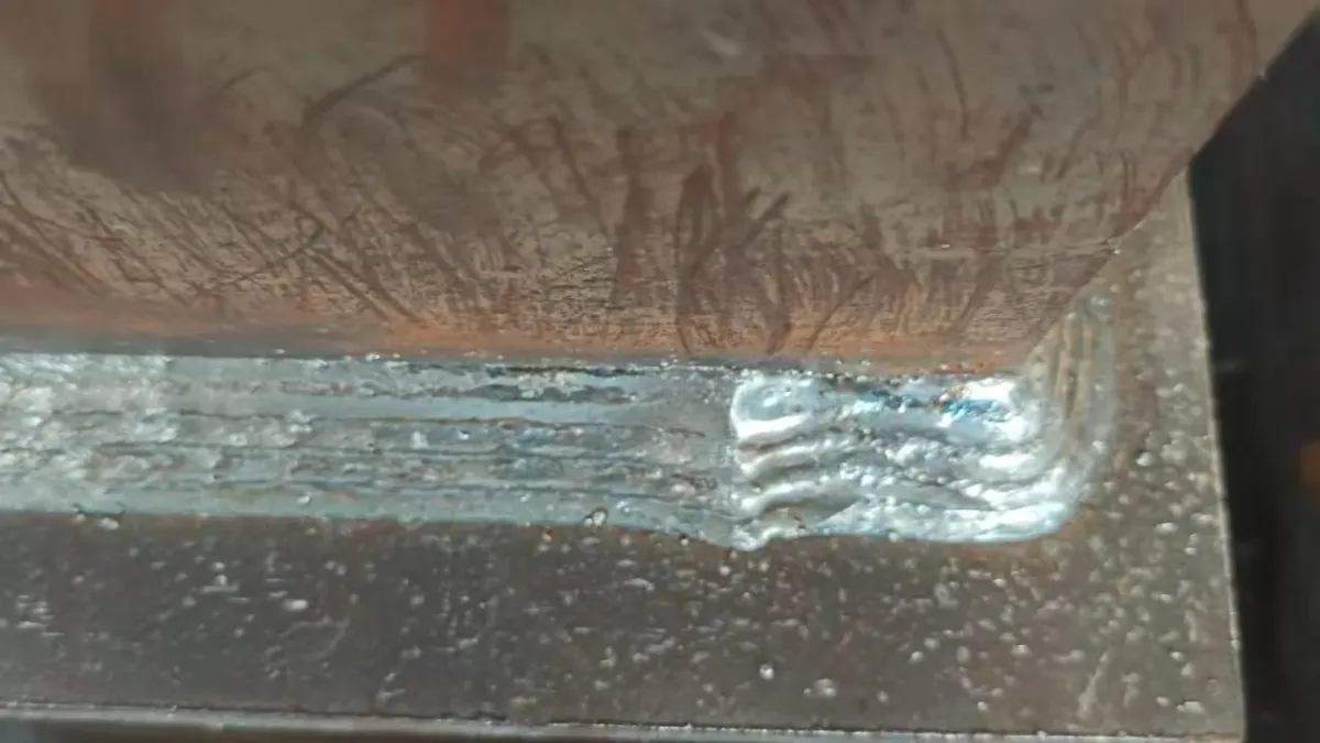 Close view of a robotic fillet weld on steel plate.